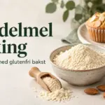 En skål med mandelmel, hele mandler og gylne muffins med mandelflak ved siden av teksten «Mandelmel i baking – Slik lykkes du med glutenfri bakst».
