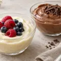 To glasskåler med kremet proteinpudding, én med vanilje og friske bær og én med sjokolade og sjokoladeflak.